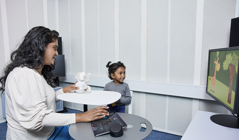 Using the Touch Keyboard, a clinician is performing VRA in an infant, who is looking toward a visual reinforcer to their left.