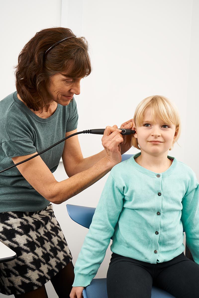 Female clinician inserting probe into young female patient’s ear