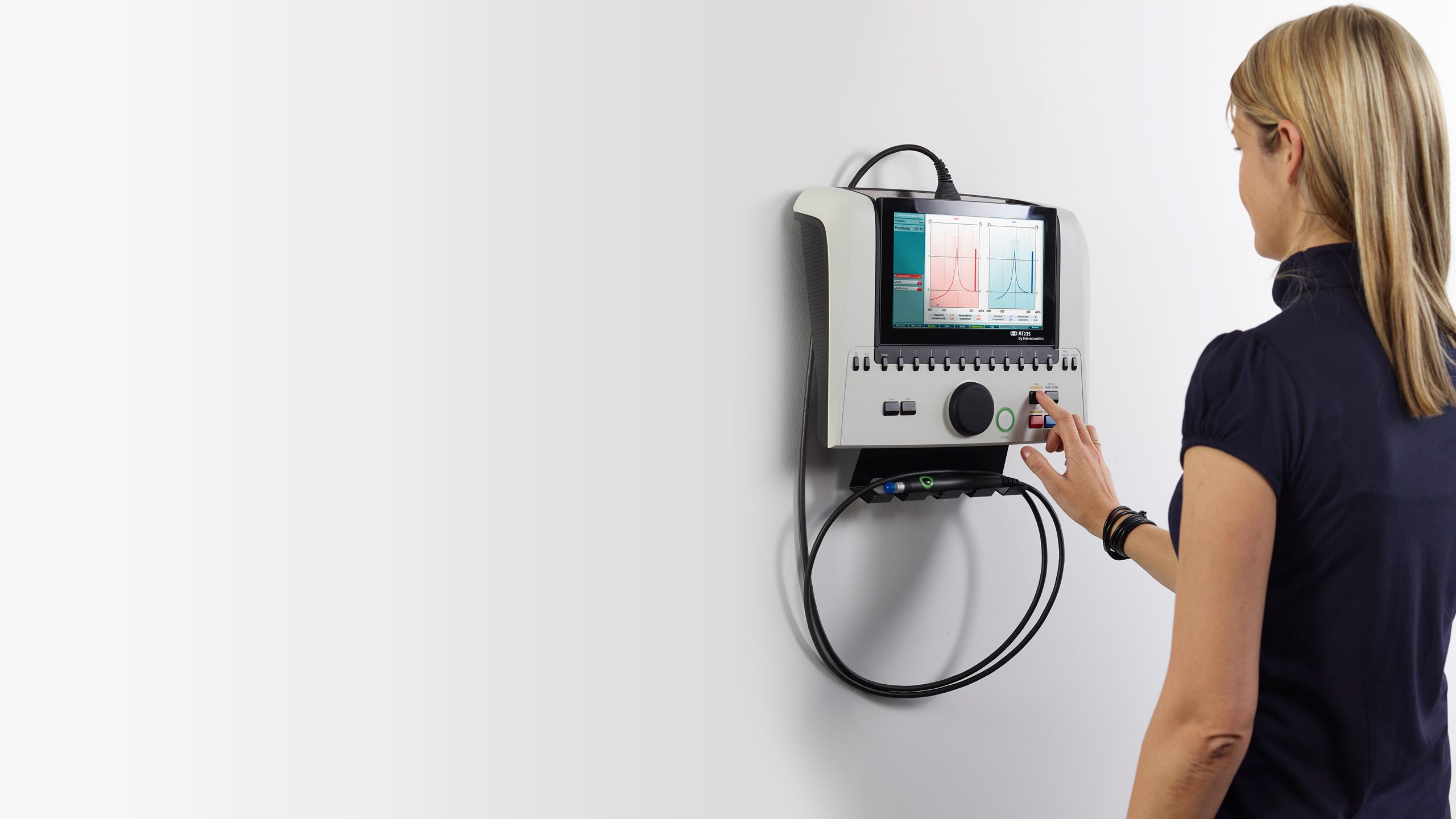 Woman pressing on wall-mounted AT235 diagnostic and clinical tympanometer