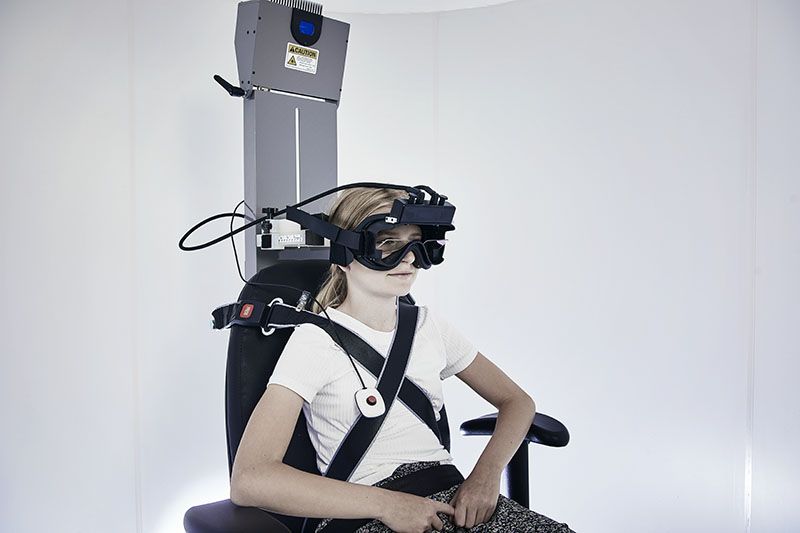 Young female patient in Orion Auto-Traverse chair wearing VNG goggles