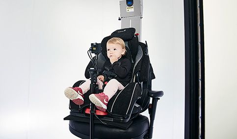 Little girl sitting in car seat, looking toward an in-booth camera