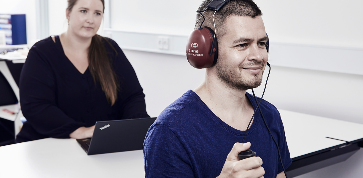 Man holding patient response button, facing away from female clinician.