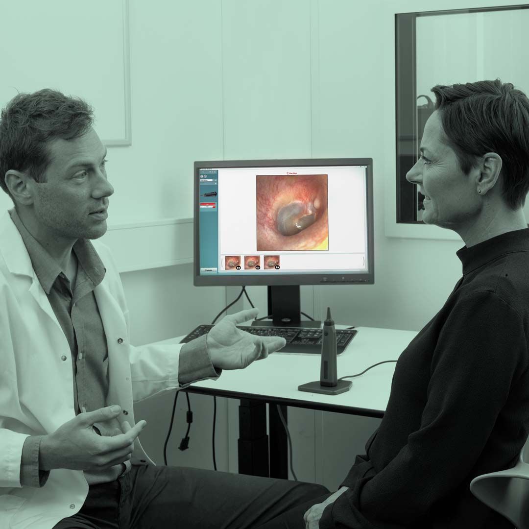 Male clinician talking to female patient after otoscopic examination.