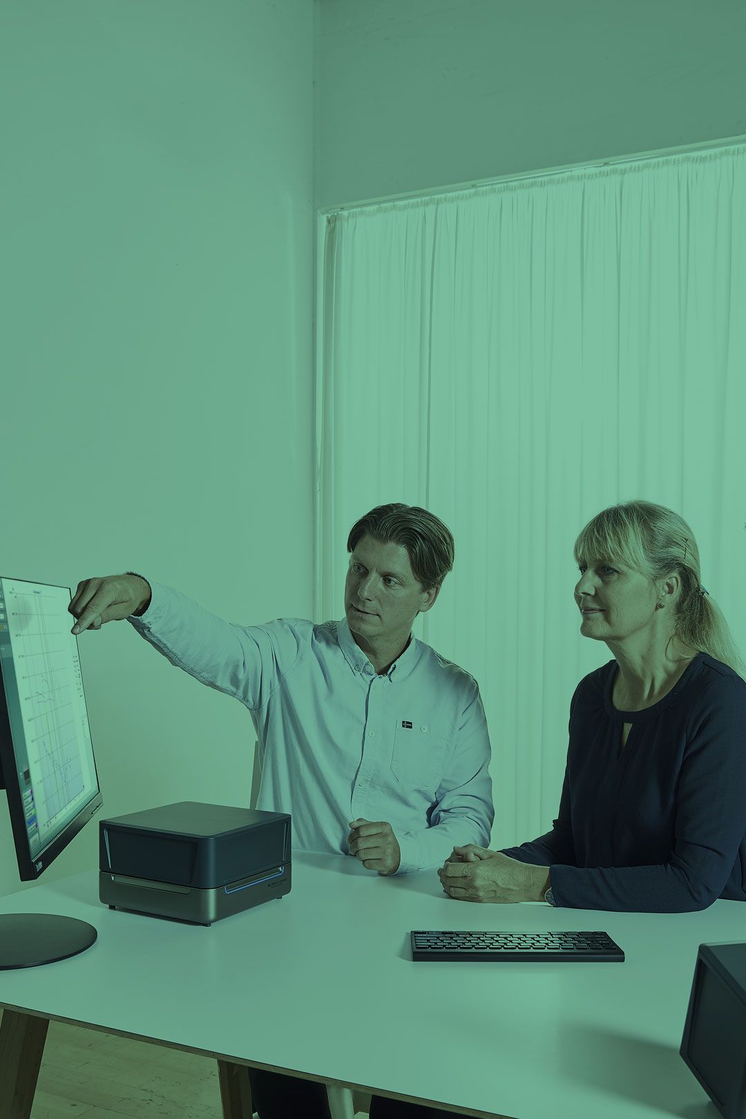 Male clinician showing female patient her visible speech mapping results on his flatscreen monitor.