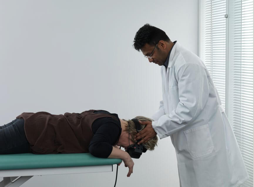 Male clinician rolling female patient onto her stomach with head hanging over the examination bed.