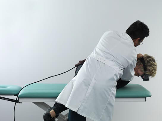 Male clinician holding female patient in a side-lying position, with the patient's head facing toward the floor.