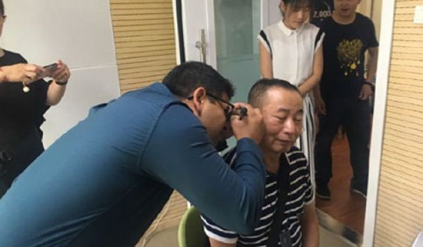 Dennis Mistry performing otoscopy on his client Cheng