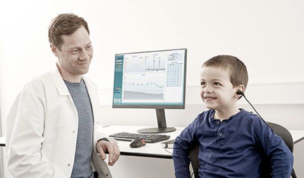 Male clinician performing otoacoustic emission testing on young boy