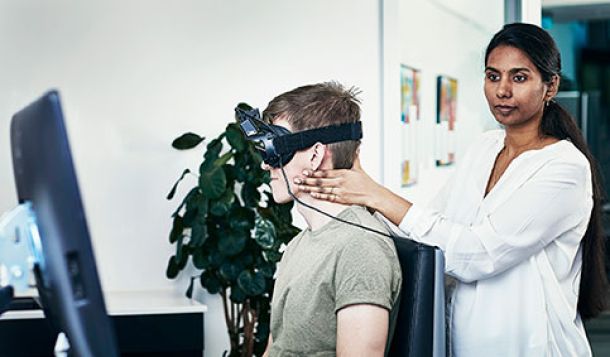 Female clinician performing head impulses on male patient