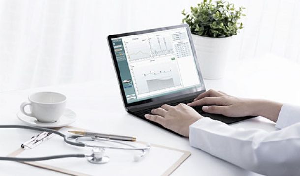 Clinician working on laptop which displays a passed DPOAE test