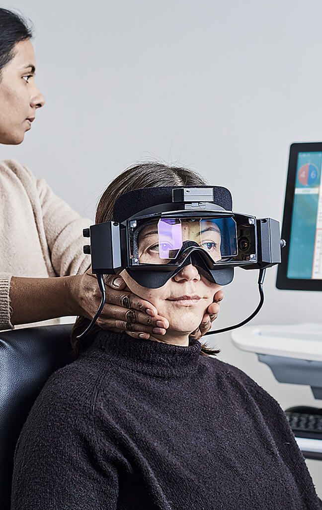 Frontal view of girl strapped into Orion Auto Traverse rotary chair, wearing VisualEyes VNG goggles