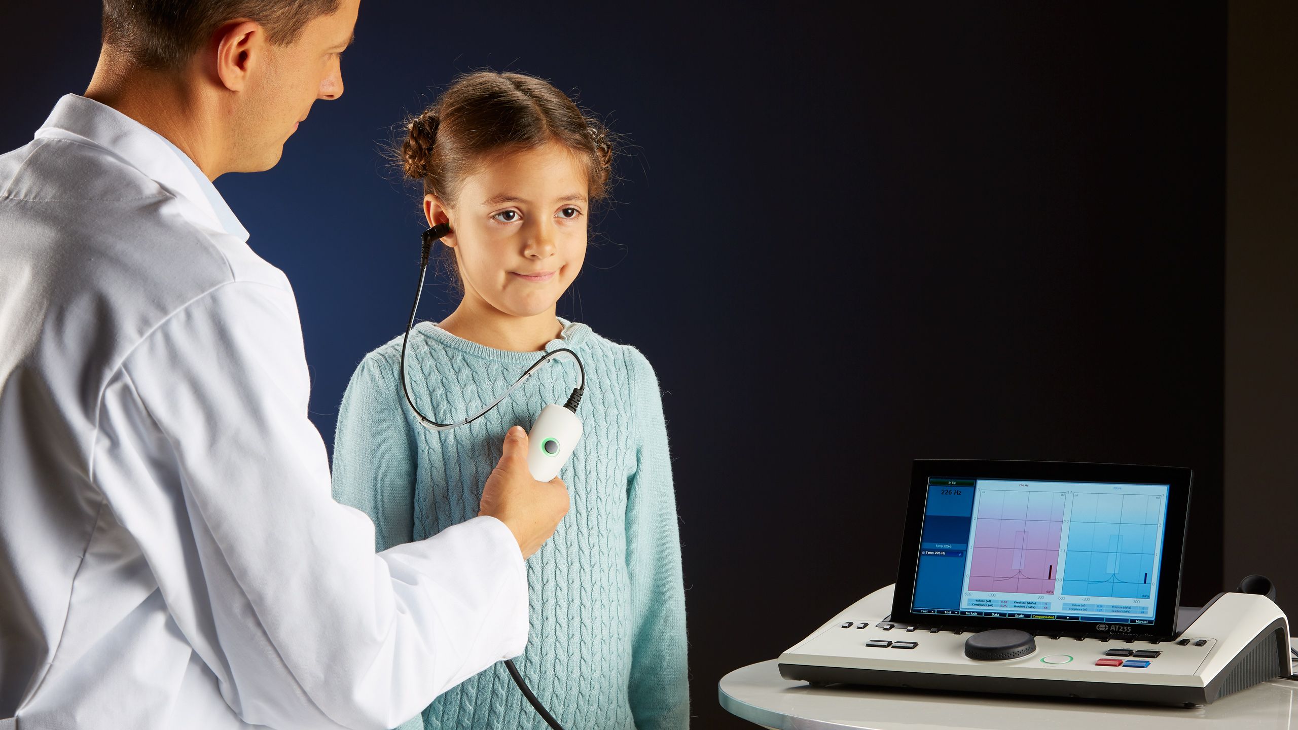 Male clinician using clinical probe to perform middle ear assessment on young female patient