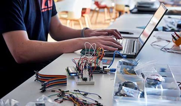 Man sat at desk with laptop, wires, cables and computer chips