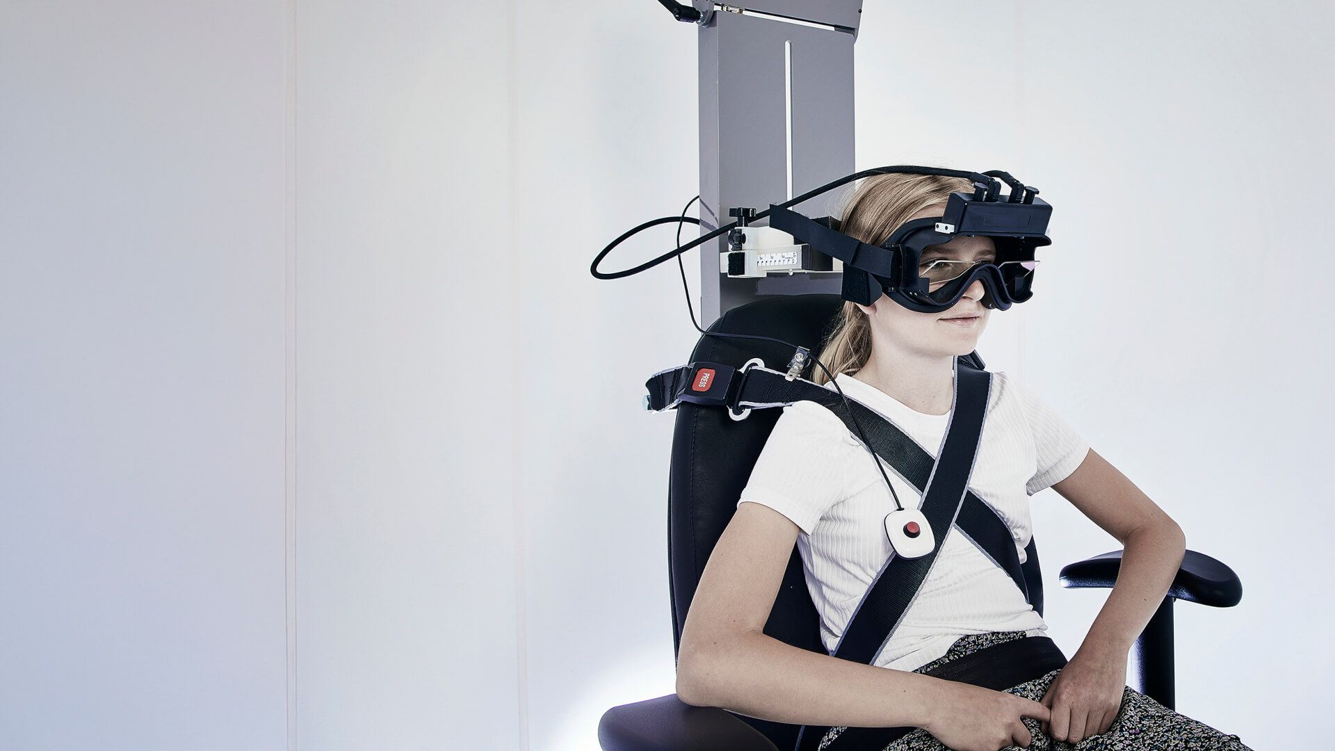 Side view of girl strapped into Orion Auto Traverse rotary chair, wearing VisualEyes VNG goggles
