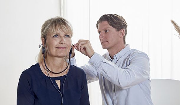 Male patient inserting REM probe tube into female client's left ear