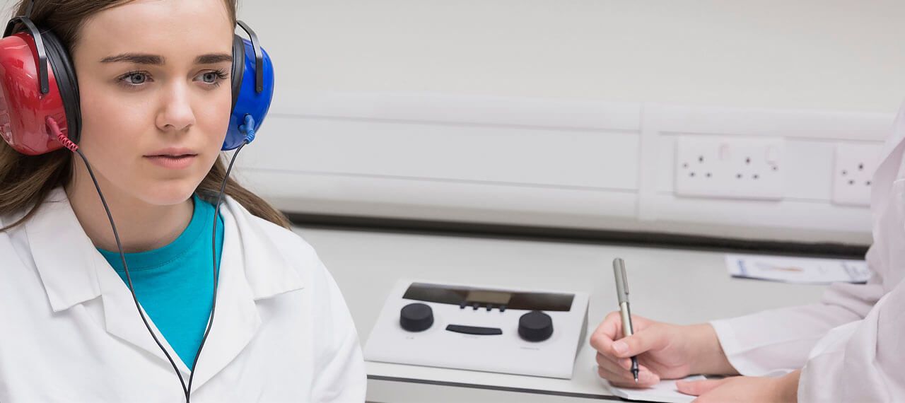 Female clinician performing hearing screening in young woman
