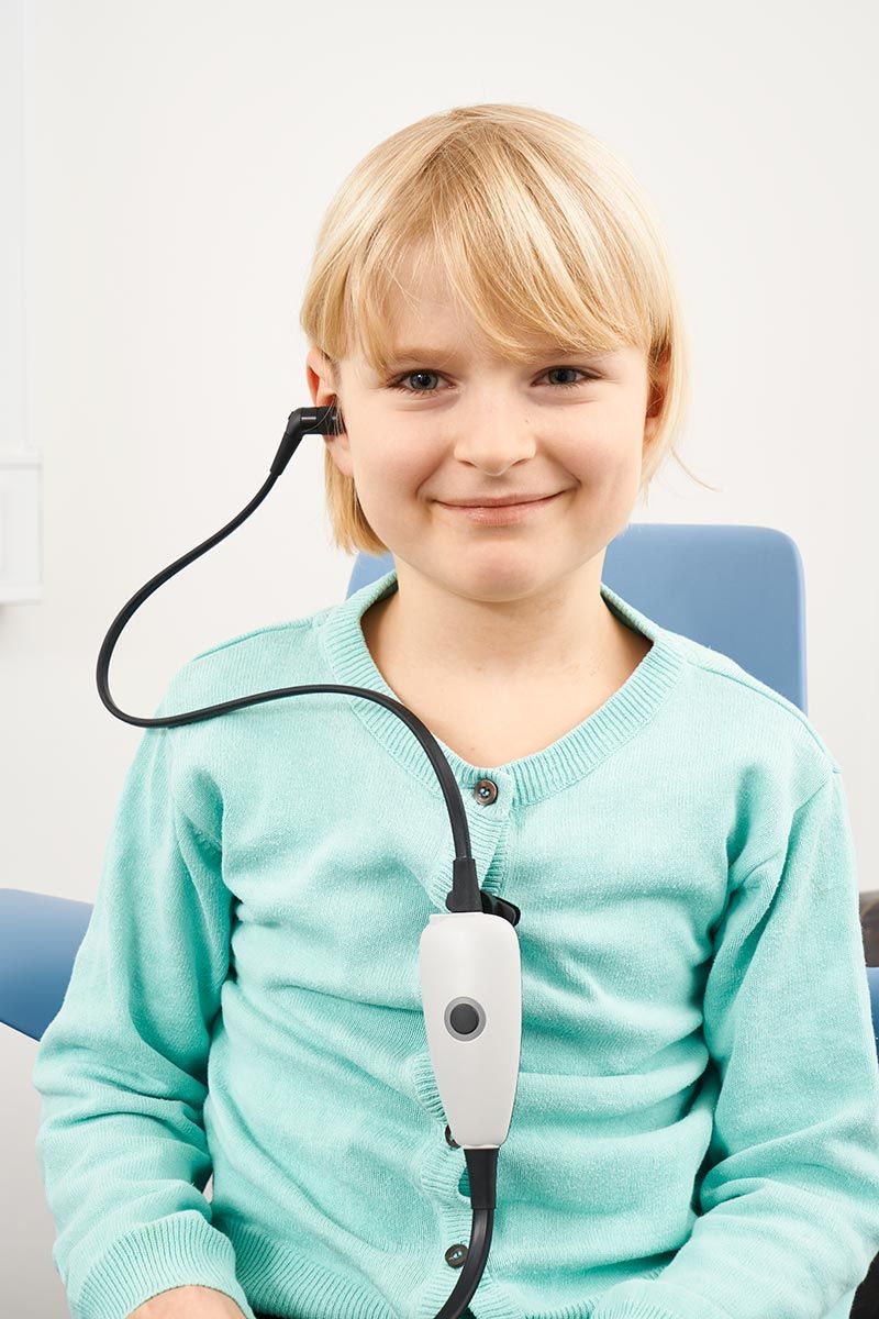 Young female patient smiling with probe in ear