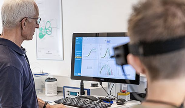 Male clinician and male patient looking at saccadometry software display on computer screen