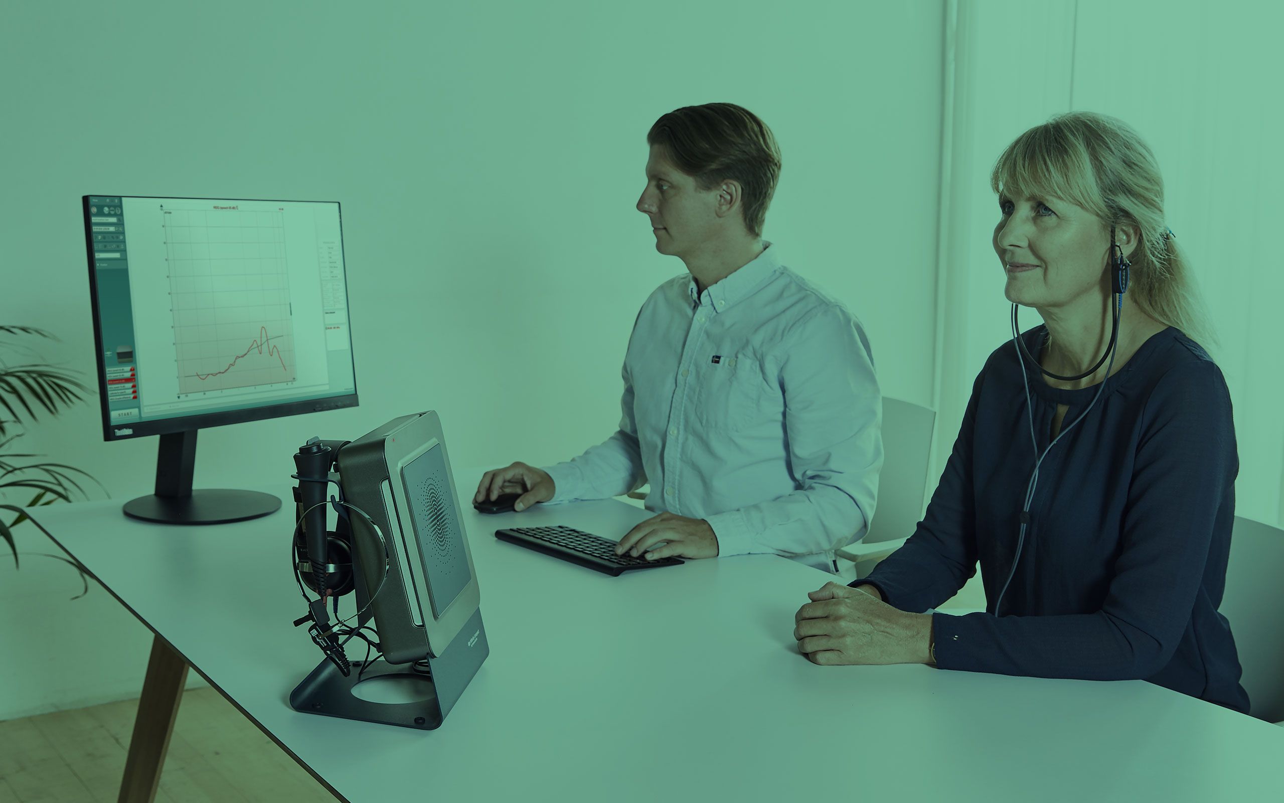 Male clinician and female patient performing real-ear measurement.