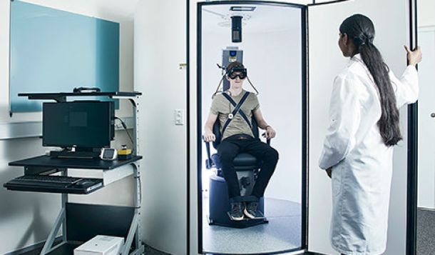 Female clinician closing door to rotary chair booth with male patient sitting inside