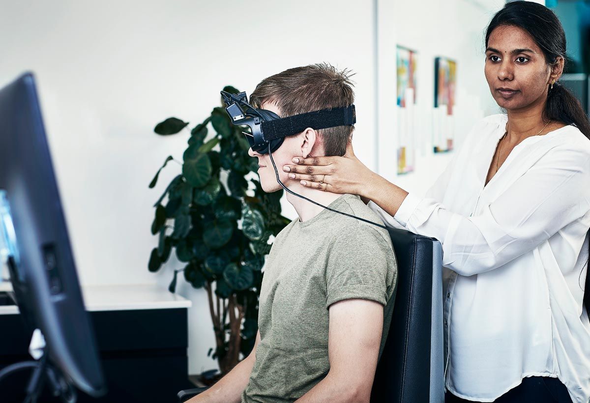Female clinician performing head thrusts on male patient wearing VNG goggles