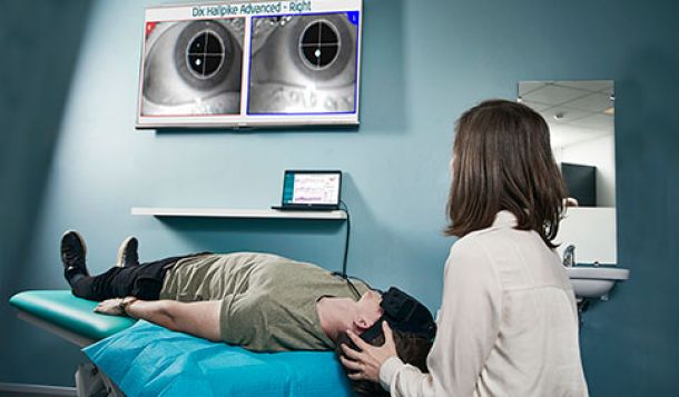 Female physical therapist performing advanced Dix-Hallpike test on male patient