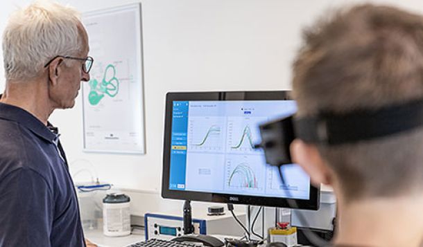 Male clinician and male patient looking toward screen with Saccadometry results