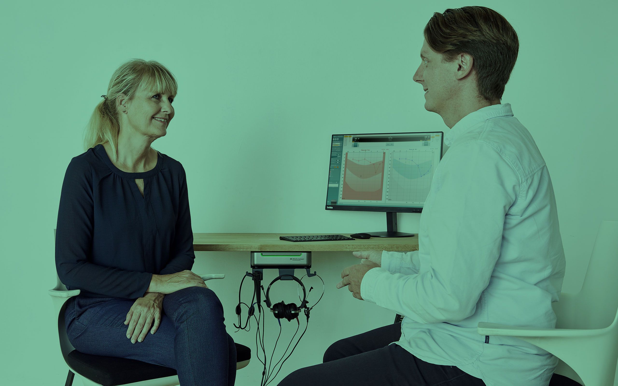 Male clinician and female patient smiling and engaged in conversation.