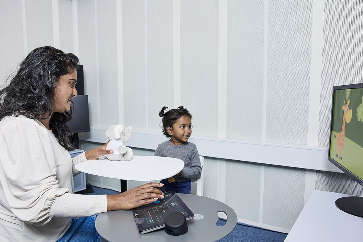 An audiologist in a sound booth with a child performing visual reinforcement audiometry 